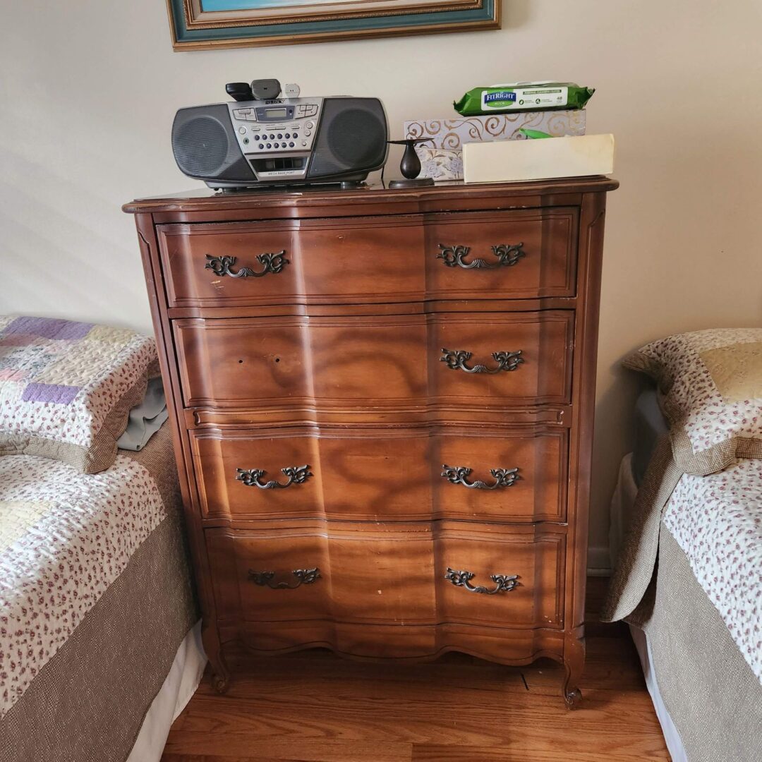 A chest of drawers in a bedroom with a radio on it.