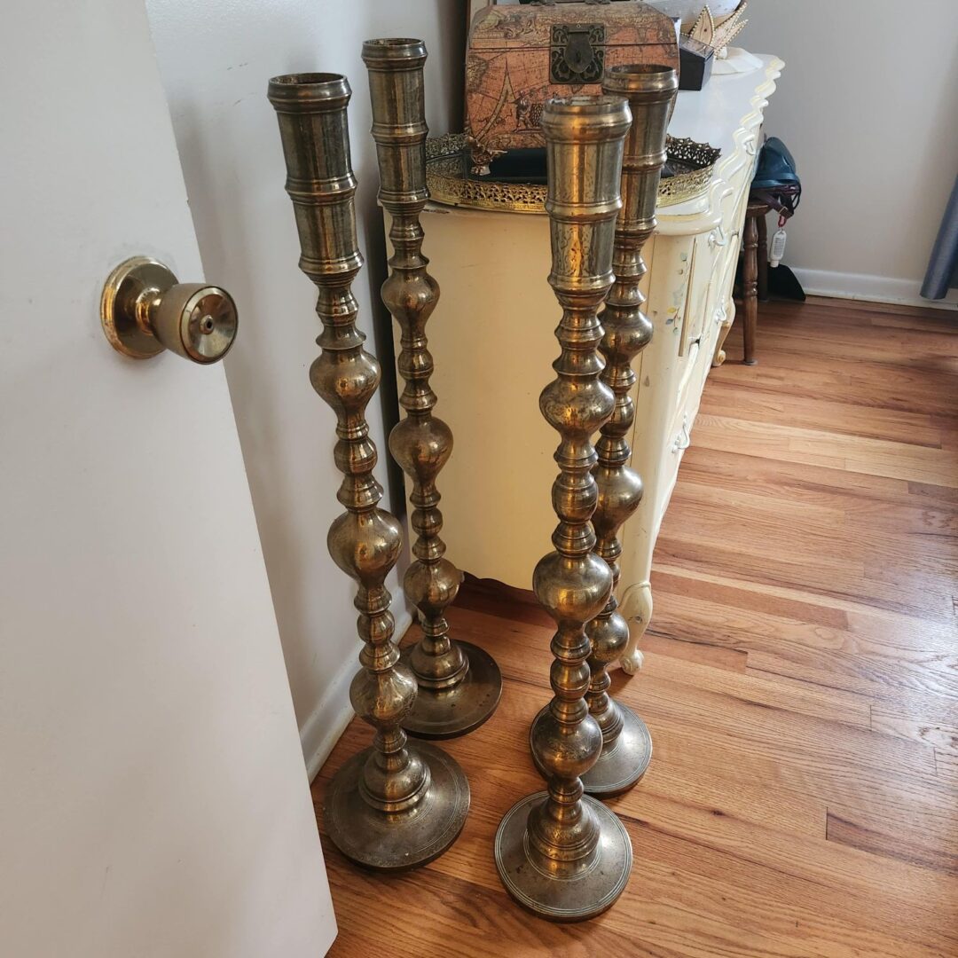 Four brass candlesticks on a wooden floor